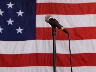 a microphone on a stand in front of a large USA flag