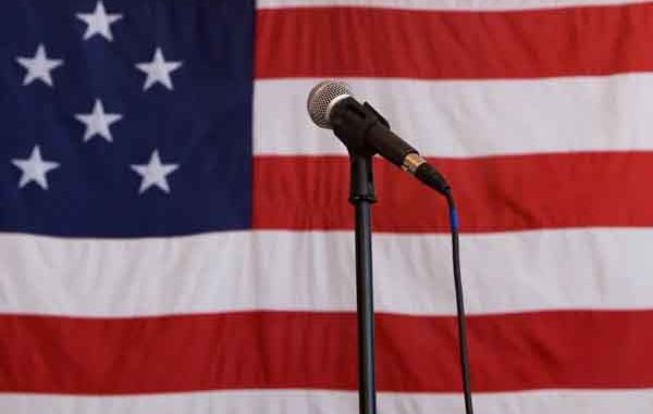 a microphone on a stand in front of a large USA flag