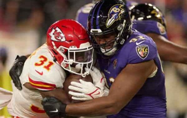 A Baltimore Ravens player tackling a Kansas City Chiefs player