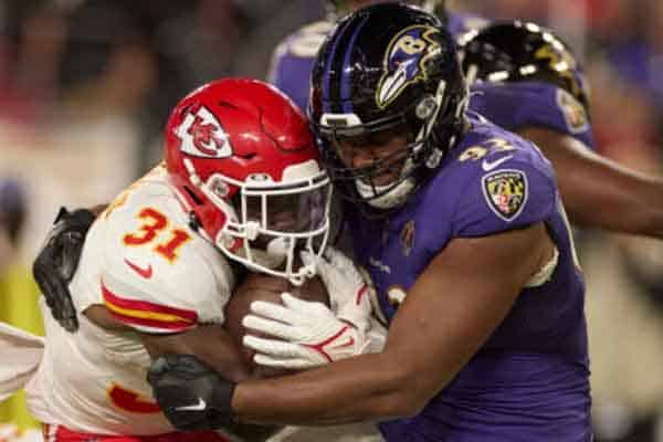 A Baltimore Ravens player tackling a Kansas City Chiefs player